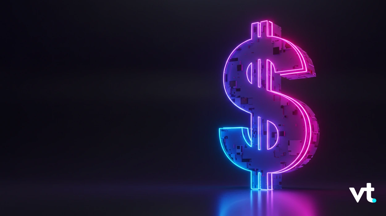Neon pink-and-blue dollar sign sculpture glowing in a dark studio with a VT logo in the lower-right corner.
